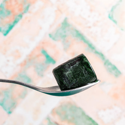 Een lepel met daarop een blokje bevroren spirulina